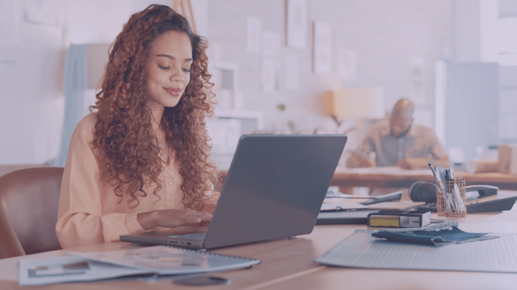 Comunicação Interna: como melhorar resultados com o uso de tecnologia? Mulher cis, branca, mexendo no computador. Comunicação Interna: como melhorar resultados com tecnologia