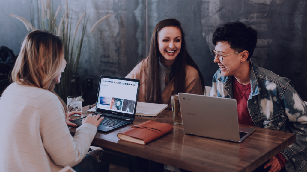 Grupo de pessoas com computador na mesa sorrindo. A jornada da marca empregadora na Raízen